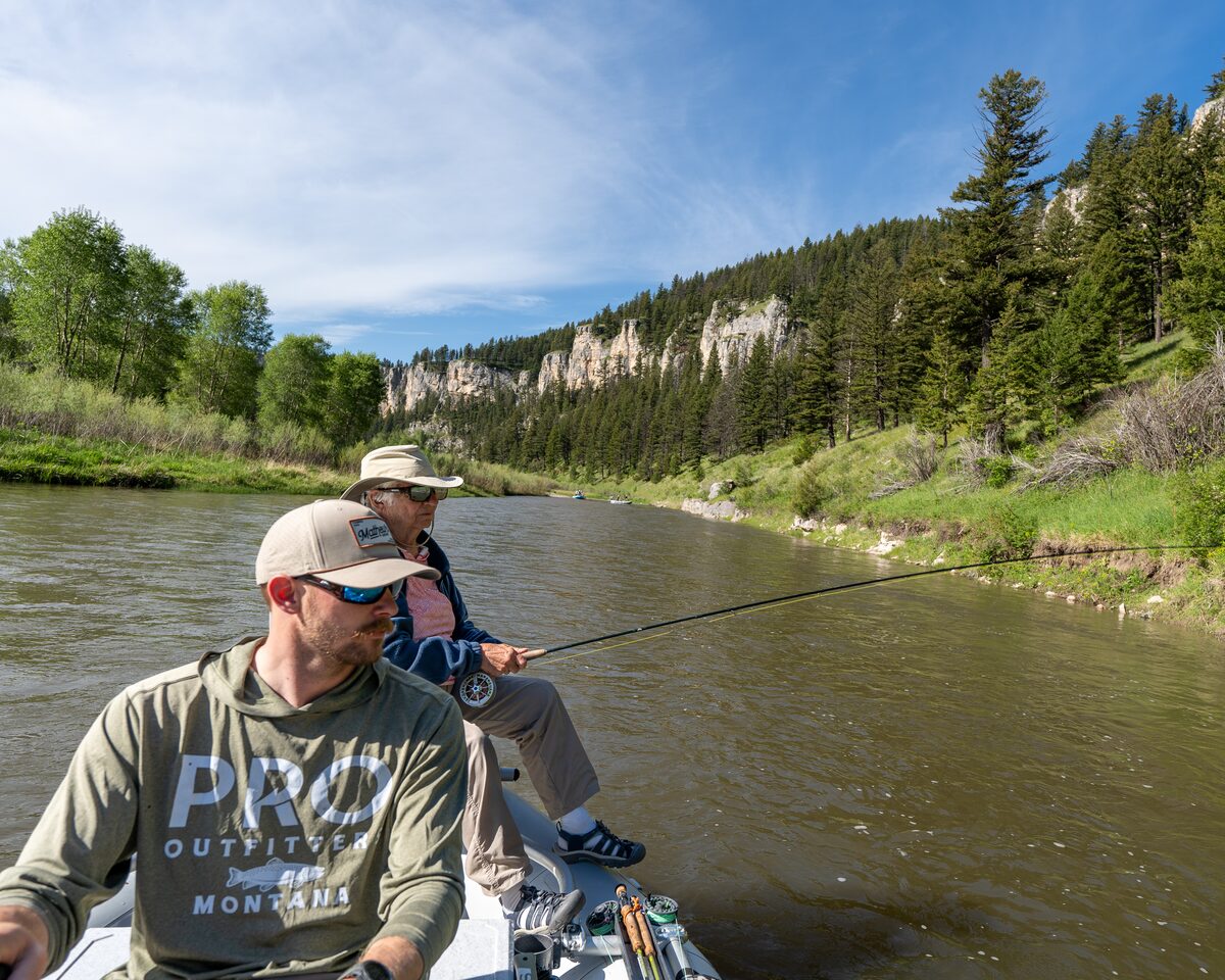 A Pro Outfitters guide at the oars while a guest casts toward the bank